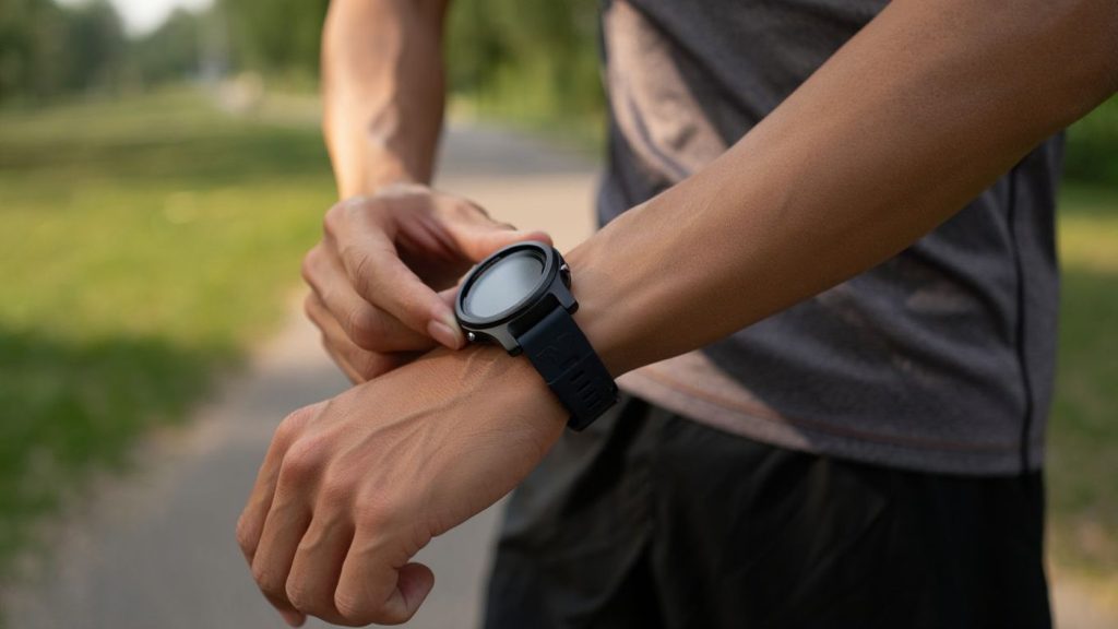 Montre de running sans marque au poignet d’un coureur sur un chemin calme