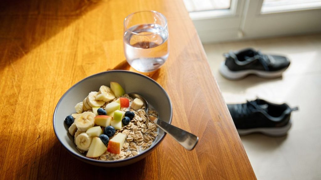Petit déjeuner équilibré après une sortie running avec bol, fruit et chaussures sans logo en arrière-plan